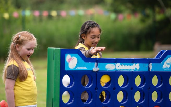 Two brownies playing connect 4 outside.